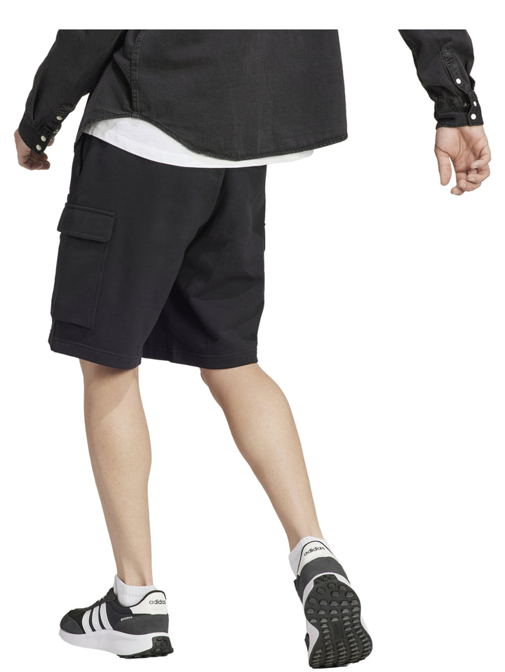 Hombre vistiendo pantalones cortos deportivos color negro de Adidas con bolsillos laterales.