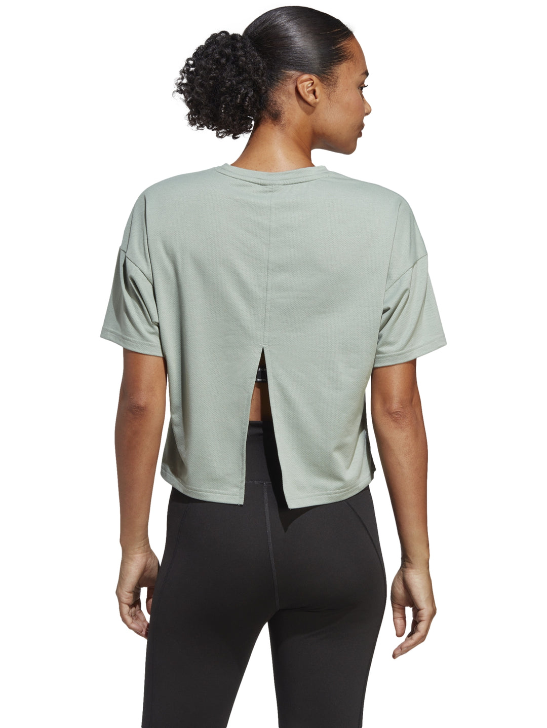 Mujer vistiendo una playera Adidas de color verde silver green con diseño de tres franjas tonales en el pecho.