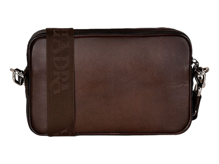 Bolso bandolera Cuadra en cuero de avestruz color chocolate con detalles plateados y correa ancha.