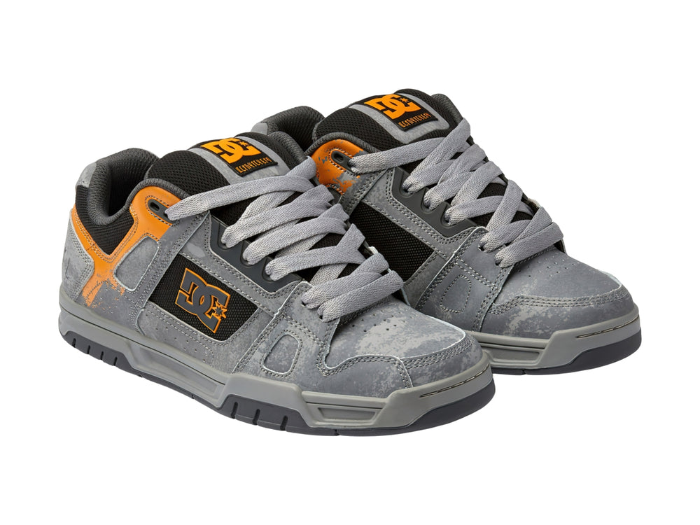 Tenis DC Shoes SW Stag color gris con detalles en naranja y negro, vista lateral.