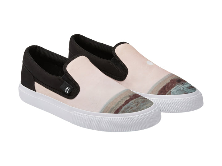 Zapato slip-on DC Shoes color beige con detalles en negro y suela blanca.