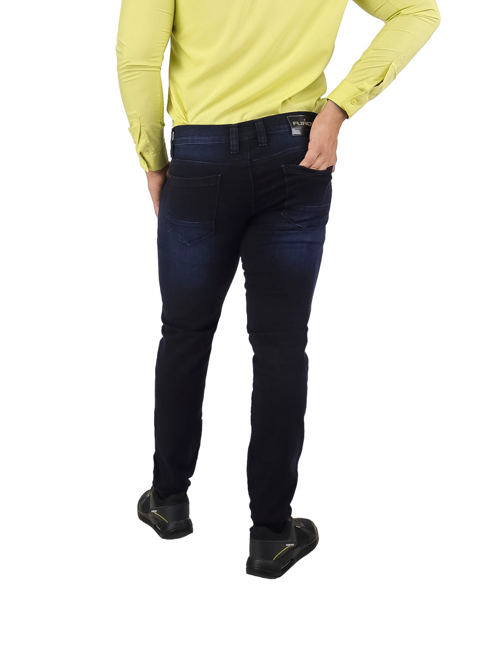 Hombre vistiendo pantalones jeans ajustados en color azul marino y camisa amarilla.