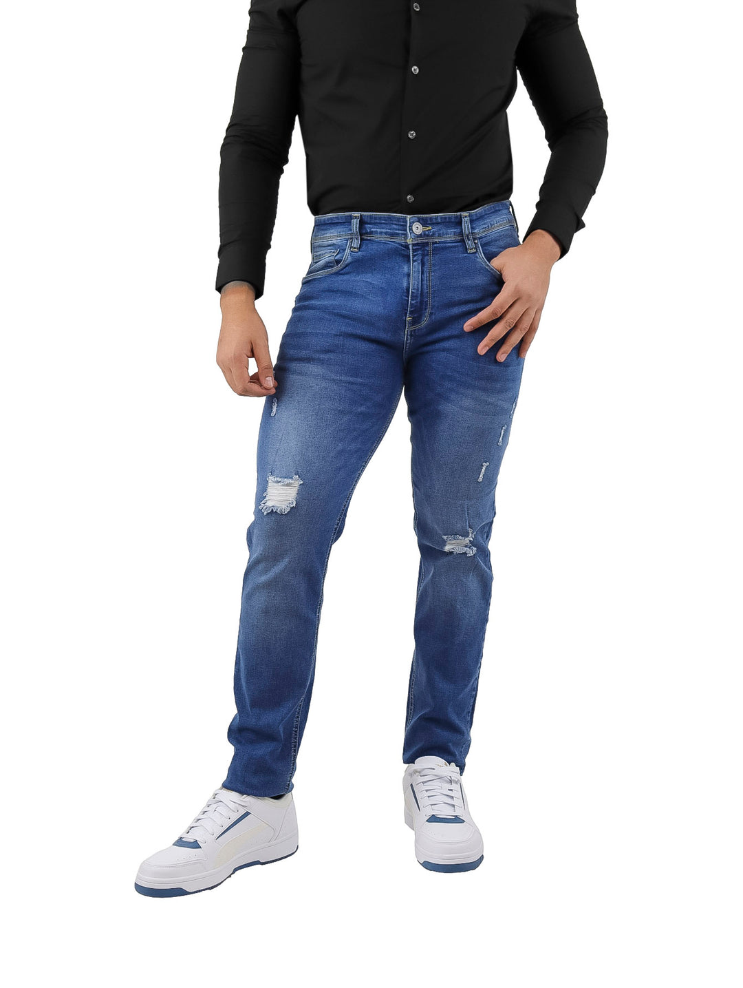 Hombre vistiendo pantalones jeans color azul con detalles rotos y calzado blanco.