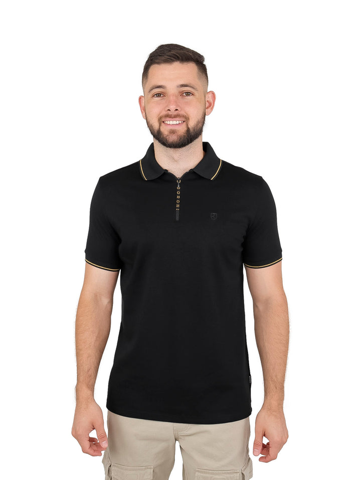 Hombre vistiendo playera polo negra con cierre y detalles en color oro en el cuello y bordes de las mangas.