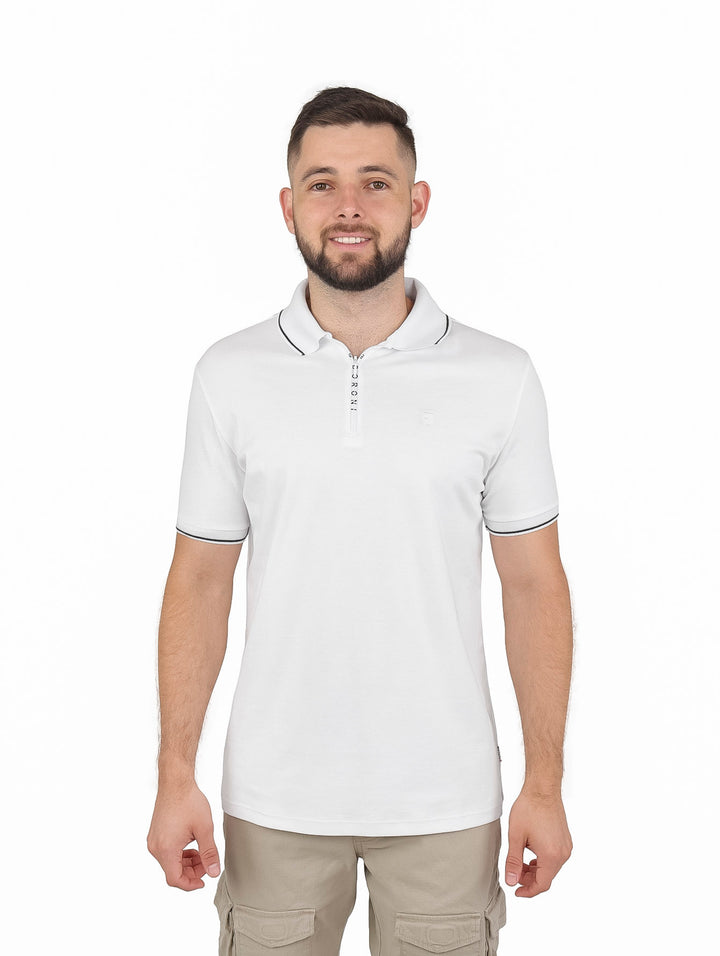 Hombre vistiendo playera polo blanca con cierre y detalles en negro en cuello y mangas.
