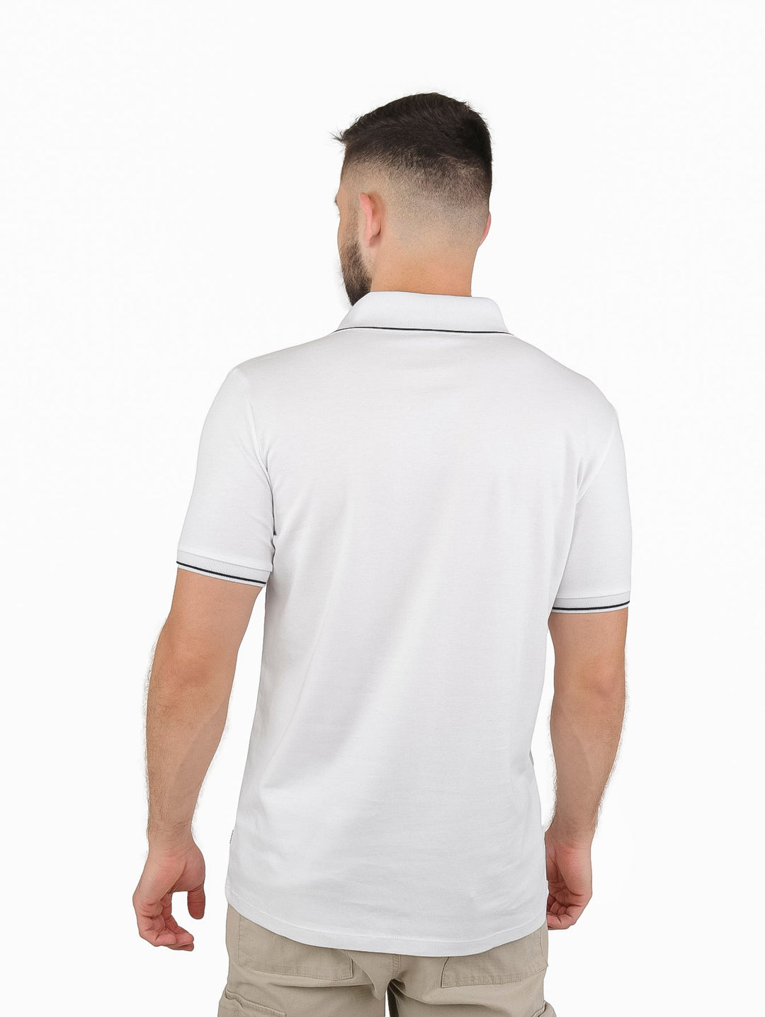 Hombre vistiendo playera polo blanca con cierre y detalles en negro en cuello y mangas.