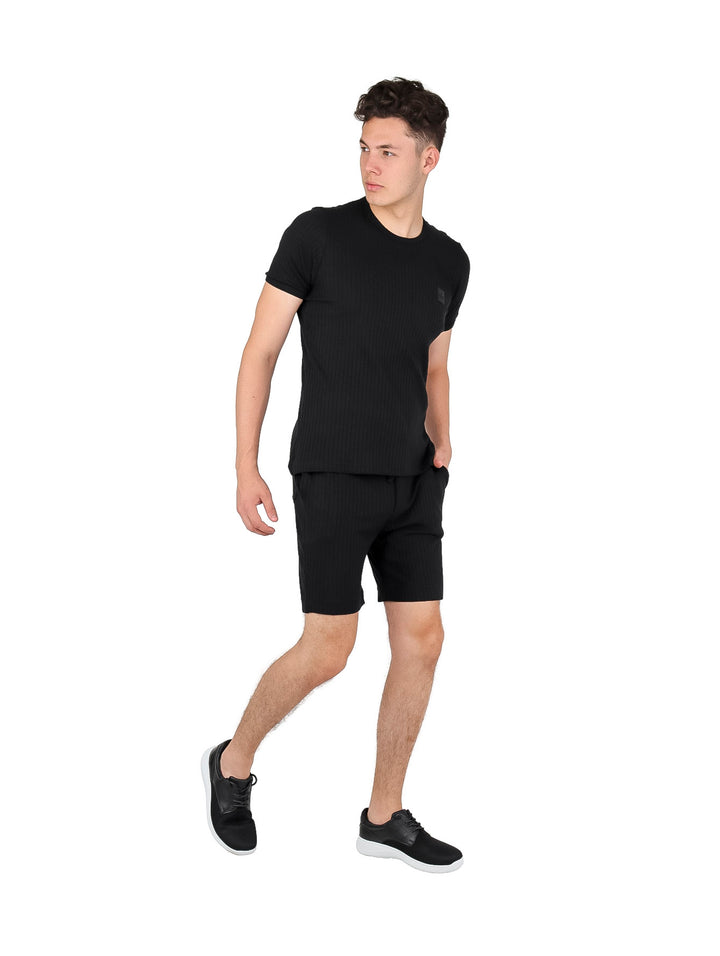 Hombre vistiendo conjunto de playera de manga corta y short en color negro.
