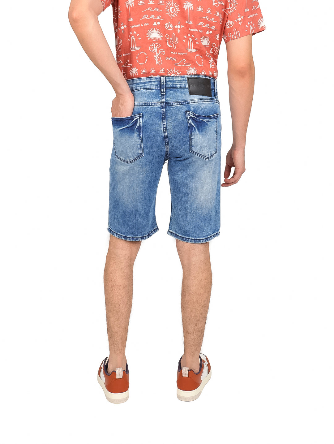 Hombre vistiendo shorts de mezclilla azul claro de corte slim.