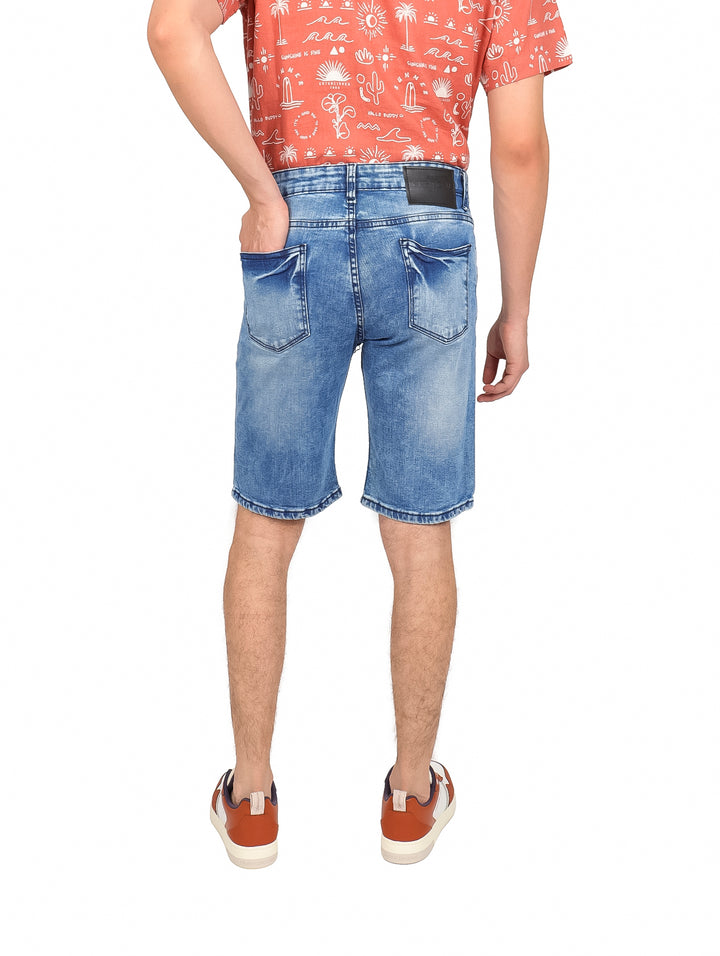 Hombre vistiendo shorts de mezclilla azul claro de corte slim.