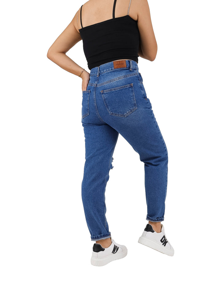 Mujer vistiendo jeans azules de corte recto con roturas en las rodillas y sin bastilla.