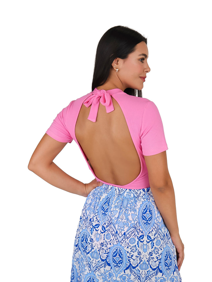 Mujer vistiendo una blusa rosa de manga corta y cuello redondo con una falda estampada en azul y blanco.