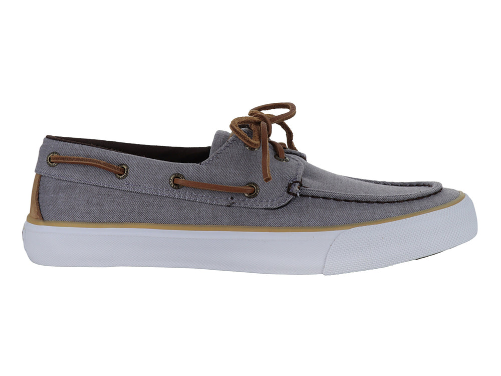 Zapato náutico Sperry de tela gris con cordones cafés y suela blanca.