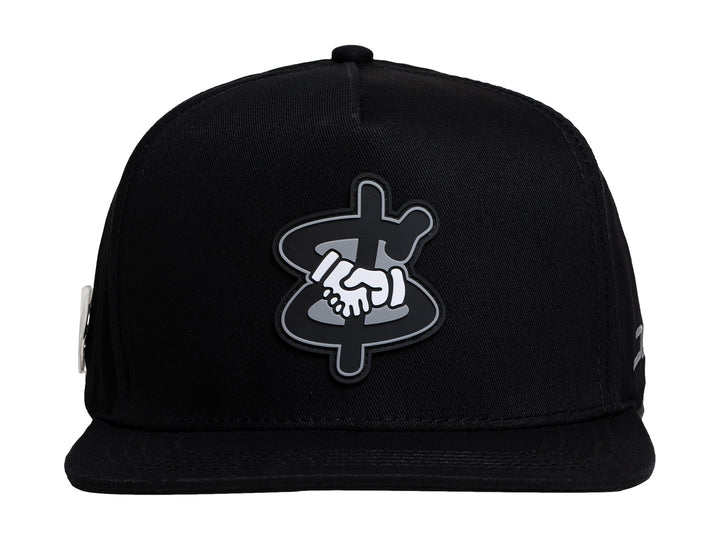 Gorra snapback color negro con visera plana y un parche bordado en el frente que muestra un apretón de manos.
