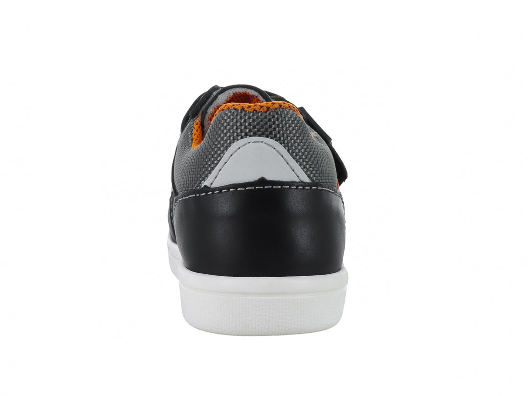 Tenis infantil color negro con detalles en gris y naranja, suela blanca y cierre de velcro.