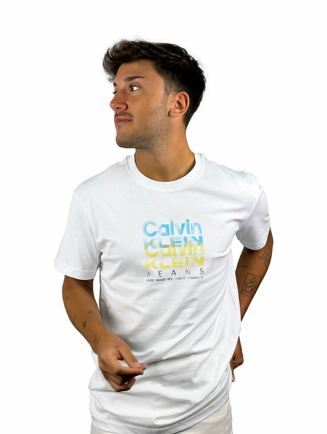 Hombre vistiendo camiseta blanca de manga corta con logo de Calvin Klein Jeans en colores degradados.