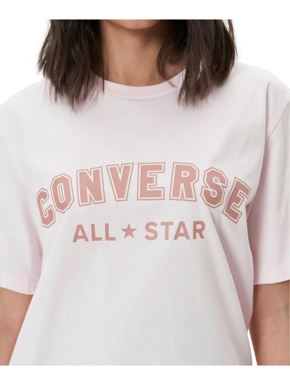 Mujer vistiendo una playera Converse de color rosa claro con logotipo en el pecho y pantalones morados.