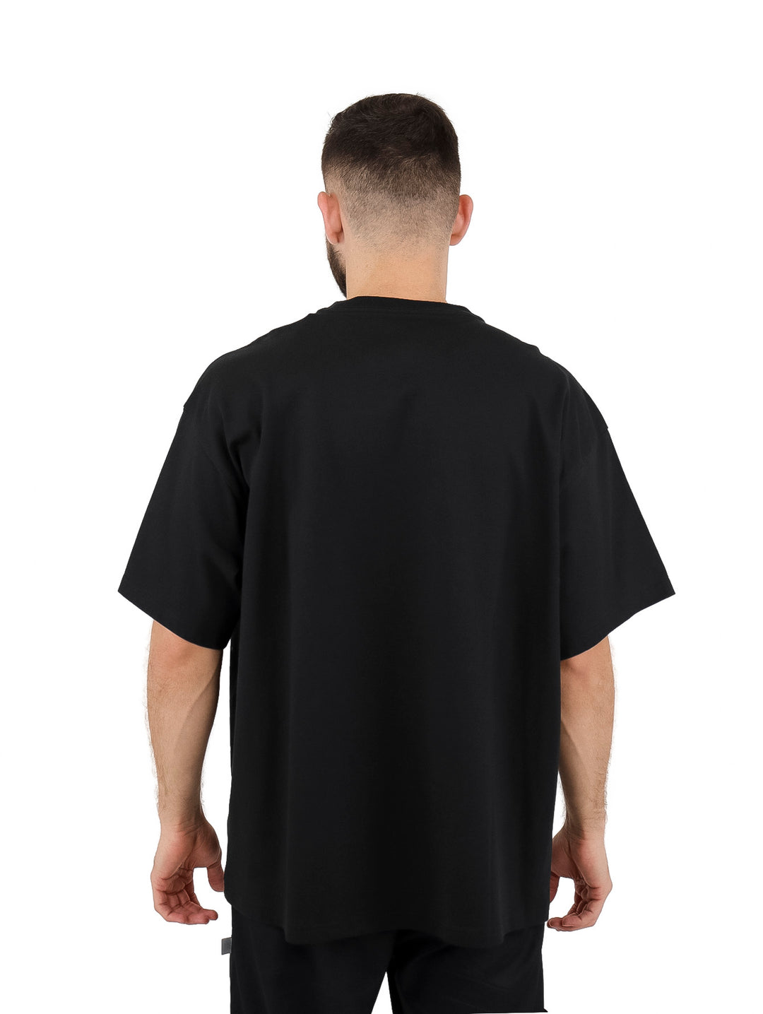 Hombre vistiendo playera negra de manga corta marca Converse con estampado gráfico blanco en el pecho.