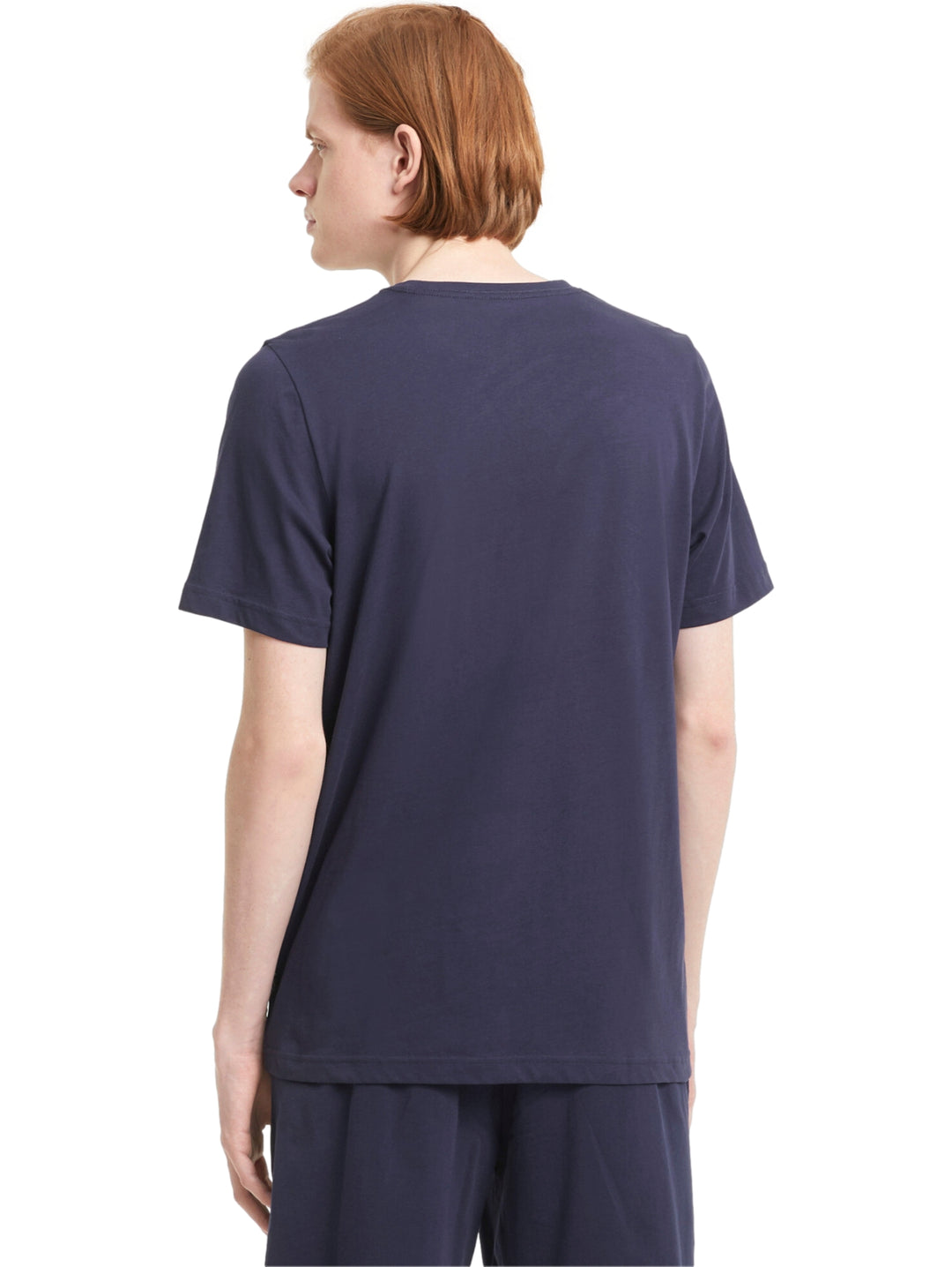 Hombre vistiendo camiseta PUMA de color azul marino con logotipo pequeño en el pecho.