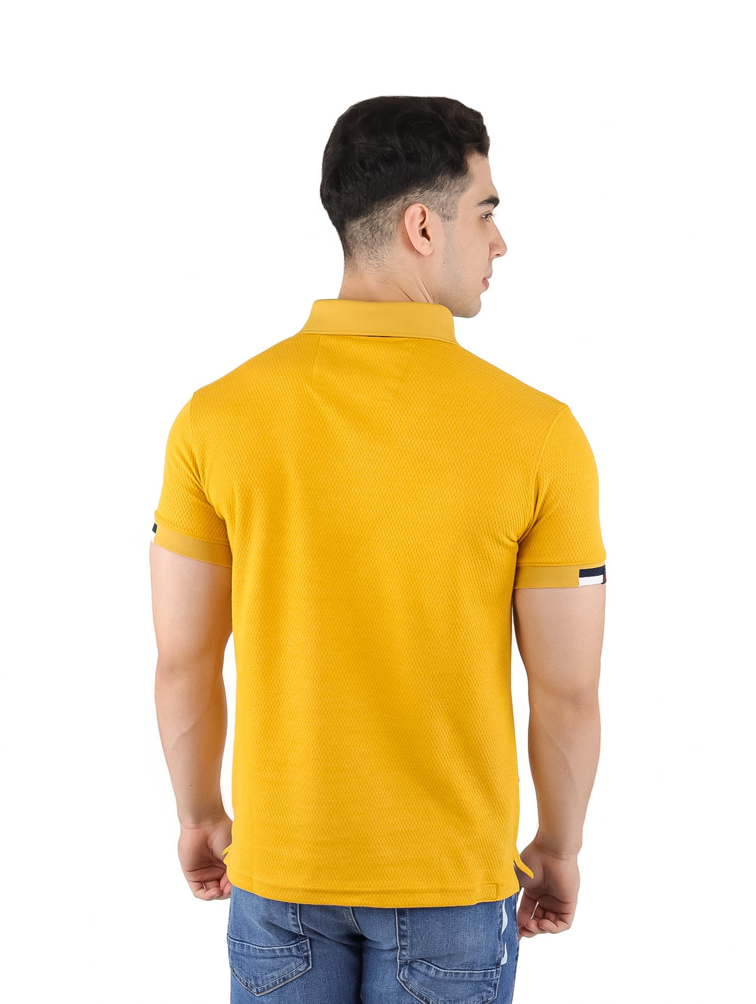 Hombre vistiendo playera polo color mostaza con cuello y detalles en azul marino y blanco.
