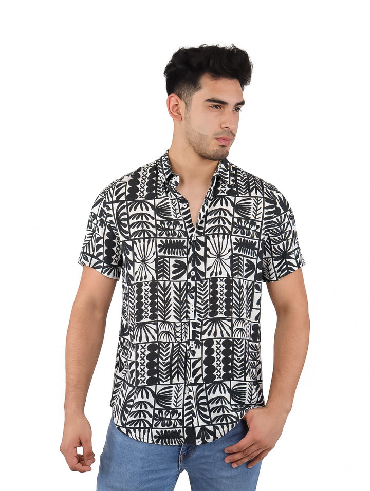 Hombre vistiendo camisa de manga corta con estampado botánico en colores blanco y negro.
