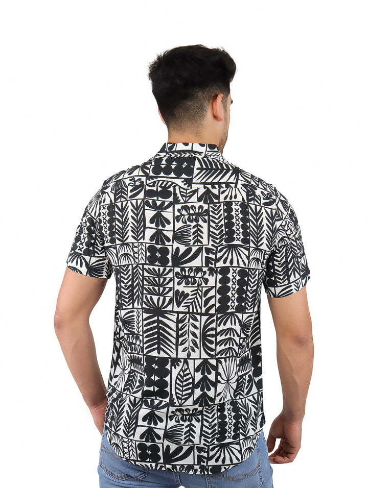 Hombre vistiendo camisa de manga corta con estampado botánico en colores blanco y negro.