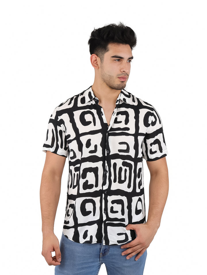 Hombre vistiendo una camisa de manga corta con estampado abstracto en colores blanco y negro.