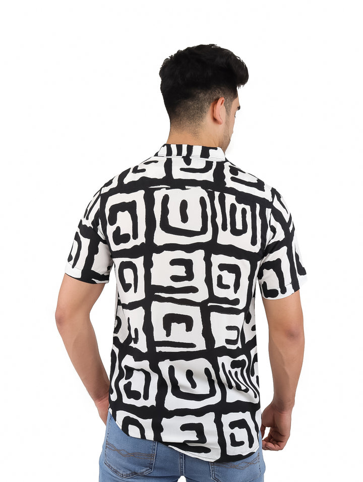 Hombre vistiendo una camisa de manga corta con estampado abstracto en colores blanco y negro.
