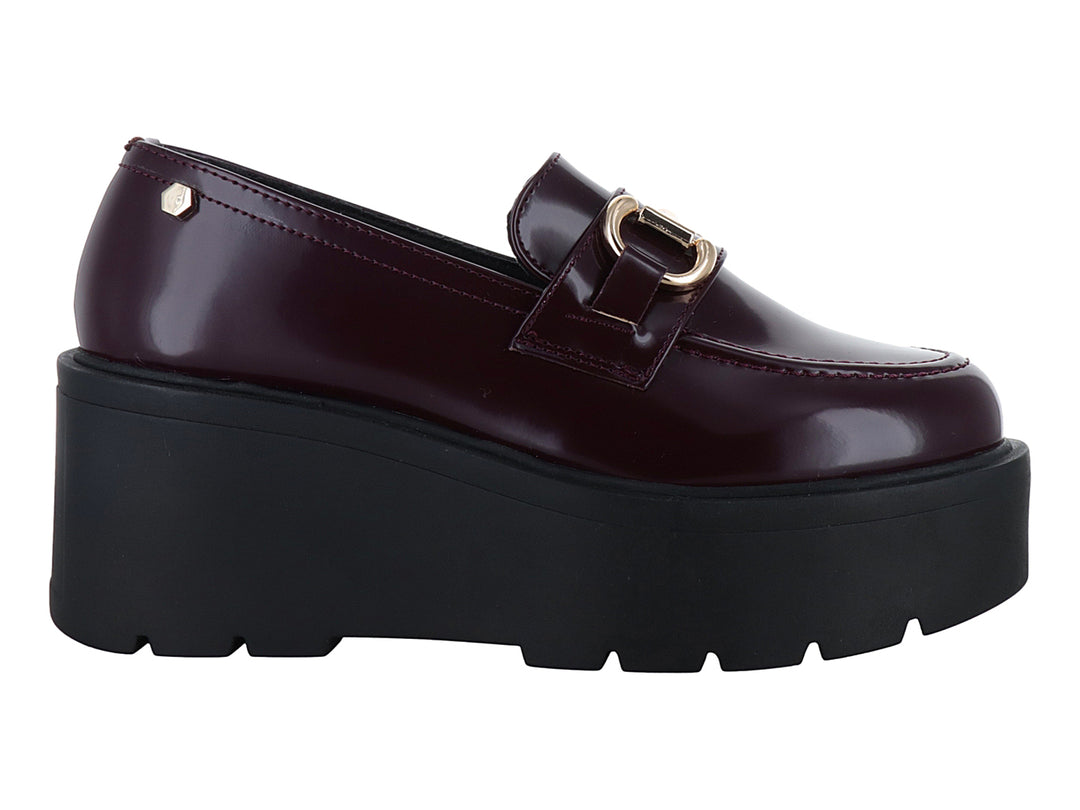 Mocasín color vino brillante con hebilla dorada y suela de plataforma negra gruesa.