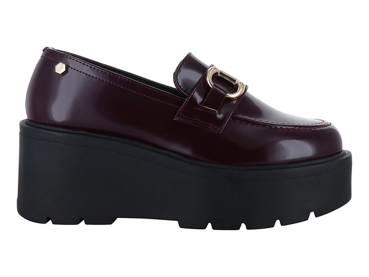 Mocasín color vino brillante con hebilla dorada y suela de plataforma negra gruesa.