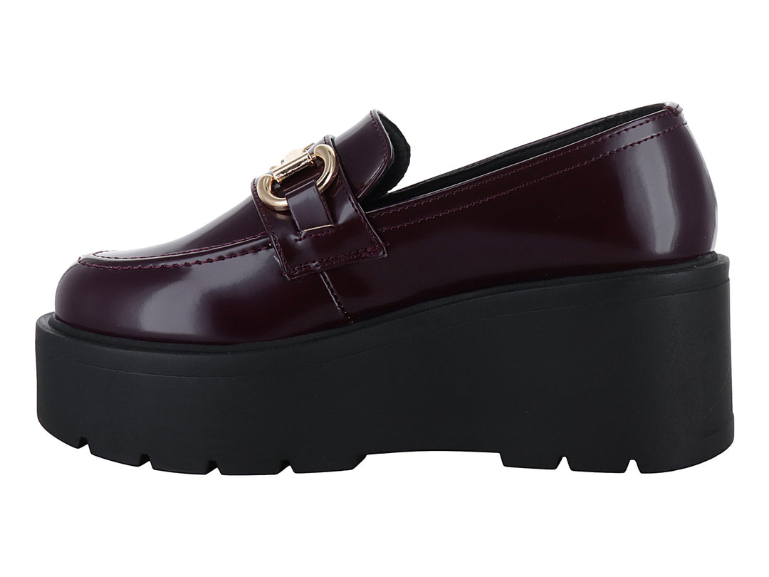 Mocasín color vino brillante con hebilla dorada y suela de plataforma negra gruesa.