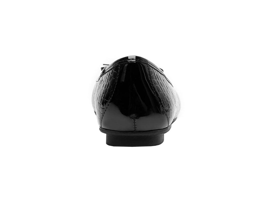 Zapato plano negro con acabado brillante, textura de cocodrilo y un pequeño moño decorativo al frente.