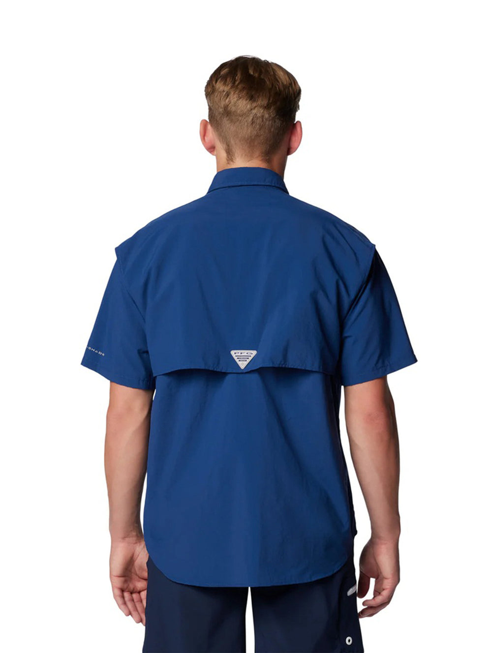Hombre vistiendo una camisa azul de manga corta marca Columbia con bolsillos frontales.