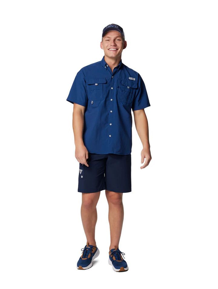 Hombre vistiendo una camisa azul de manga corta marca Columbia con bolsillos frontales.