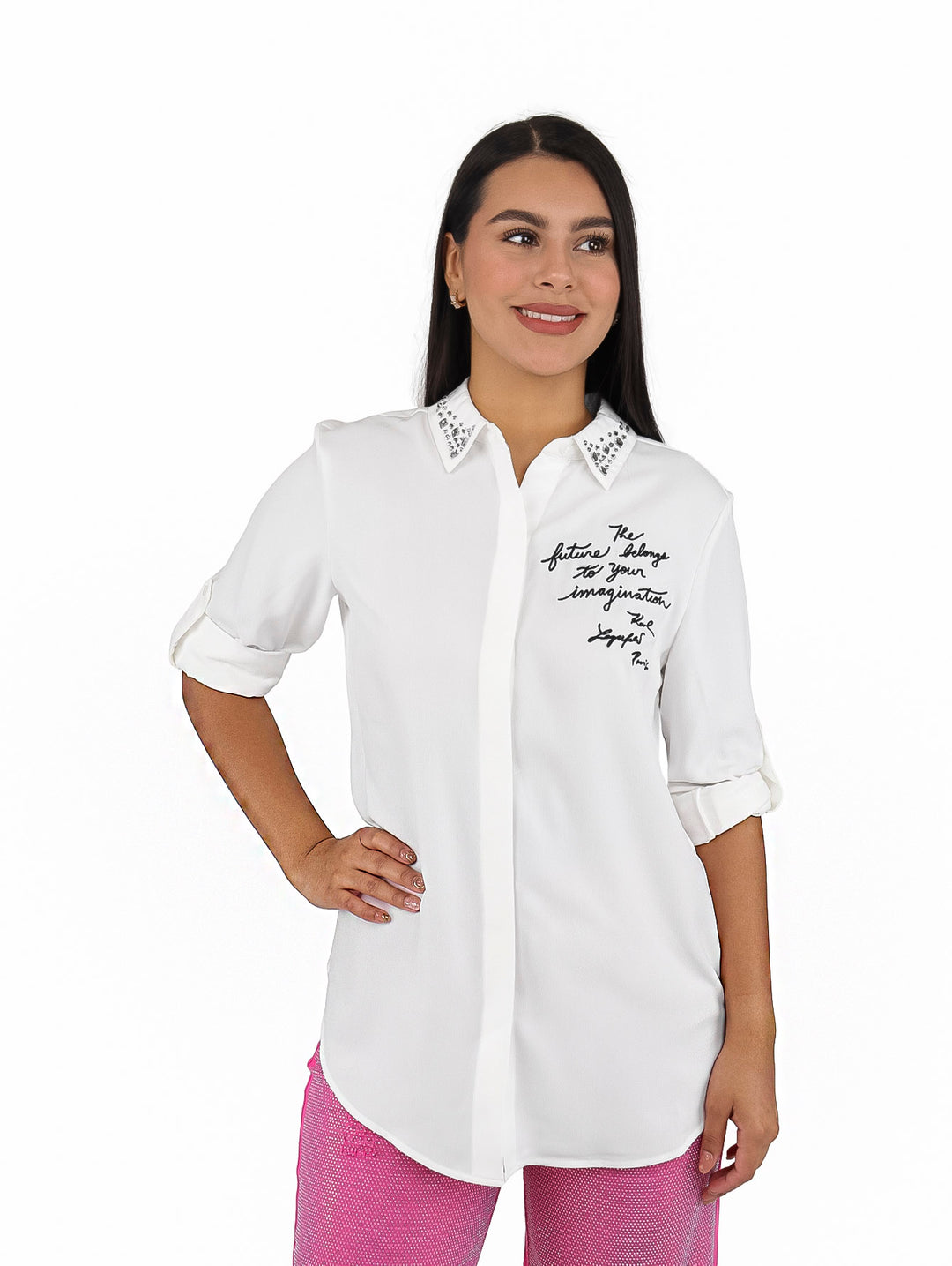 Mujer vistiendo camisa blanca de manga larga con tachuelas en el cuello y texto en el pecho.