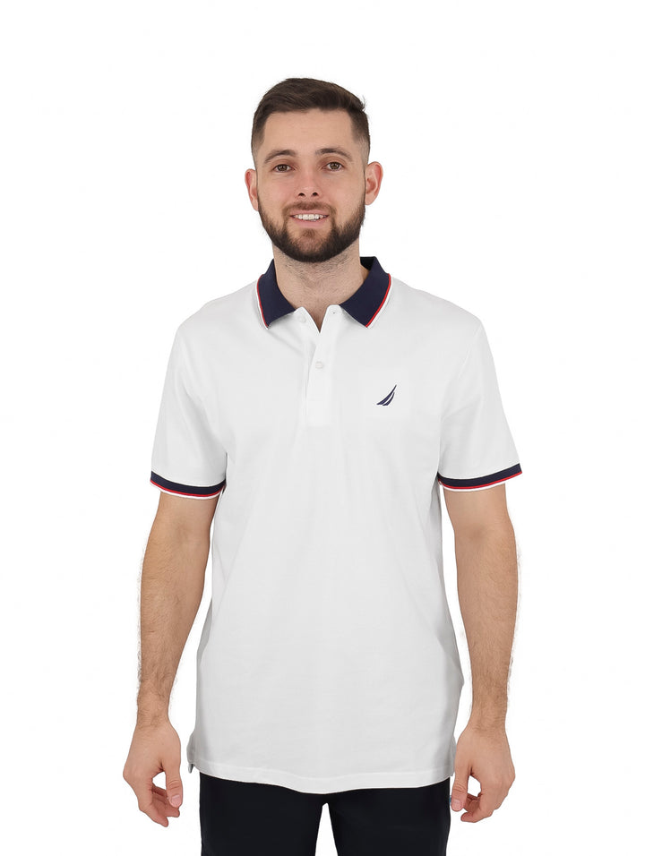 Hombre vistiendo playera polo blanca con cuello y bordes de manga en azul marino y rojo.