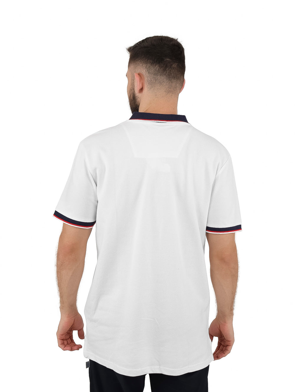 Hombre vistiendo playera polo blanca con cuello y bordes de manga en azul marino y rojo.