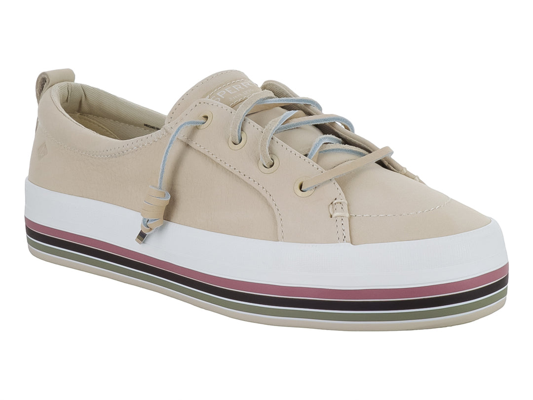Zapato Sperry color crema con suela blanca y detalles de rayas coloridas en la base.