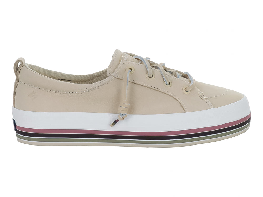 Zapato Sperry color crema con suela blanca y detalles de rayas coloridas en la base.
