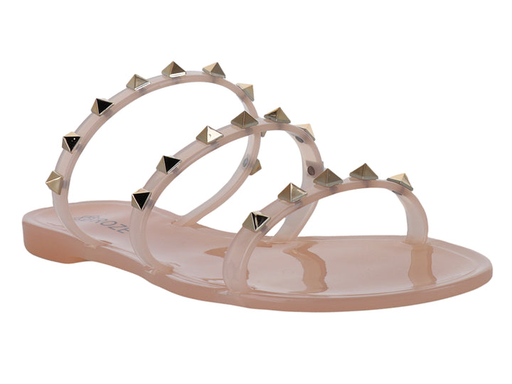 Sandalia plana color nude con tiras transparentes adornadas con tachuelas doradas.