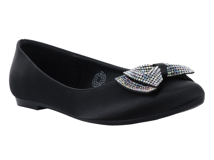 Zapatos planos negros de material brillante con un moño decorado con pedrería multicolor en la punta.