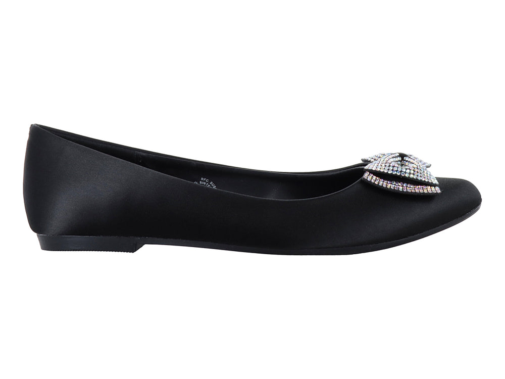 Zapatos planos negros de material brillante con un moño decorado con pedrería multicolor en la punta.