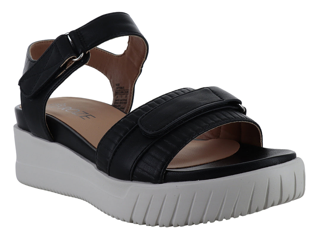 Sandalia negra de plataforma con suela blanca dentada y correa ajustable al tobillo.