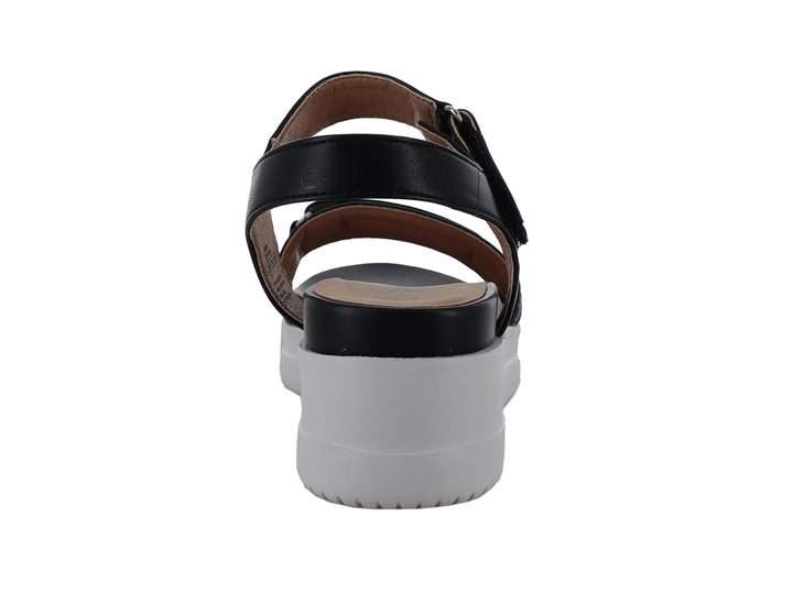 Sandalia negra de plataforma con suela blanca dentada y correa ajustable al tobillo.