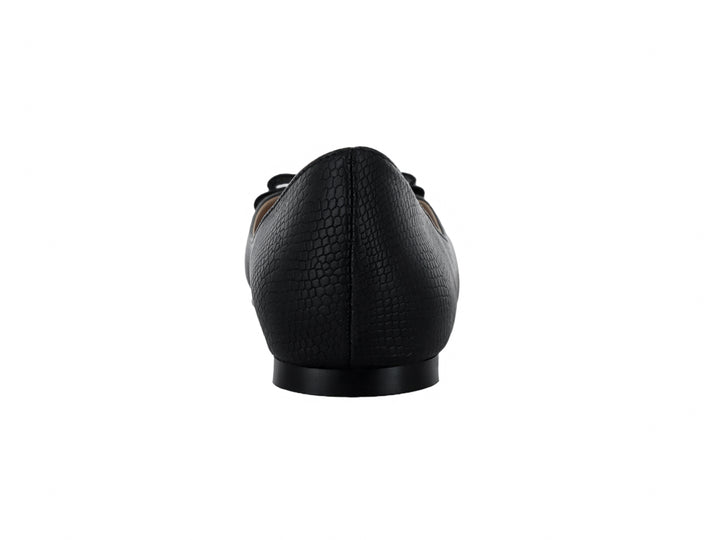 Zapato plano negro para mujer con textura de piel de anaconda y adorno de moño con detalle dorado.