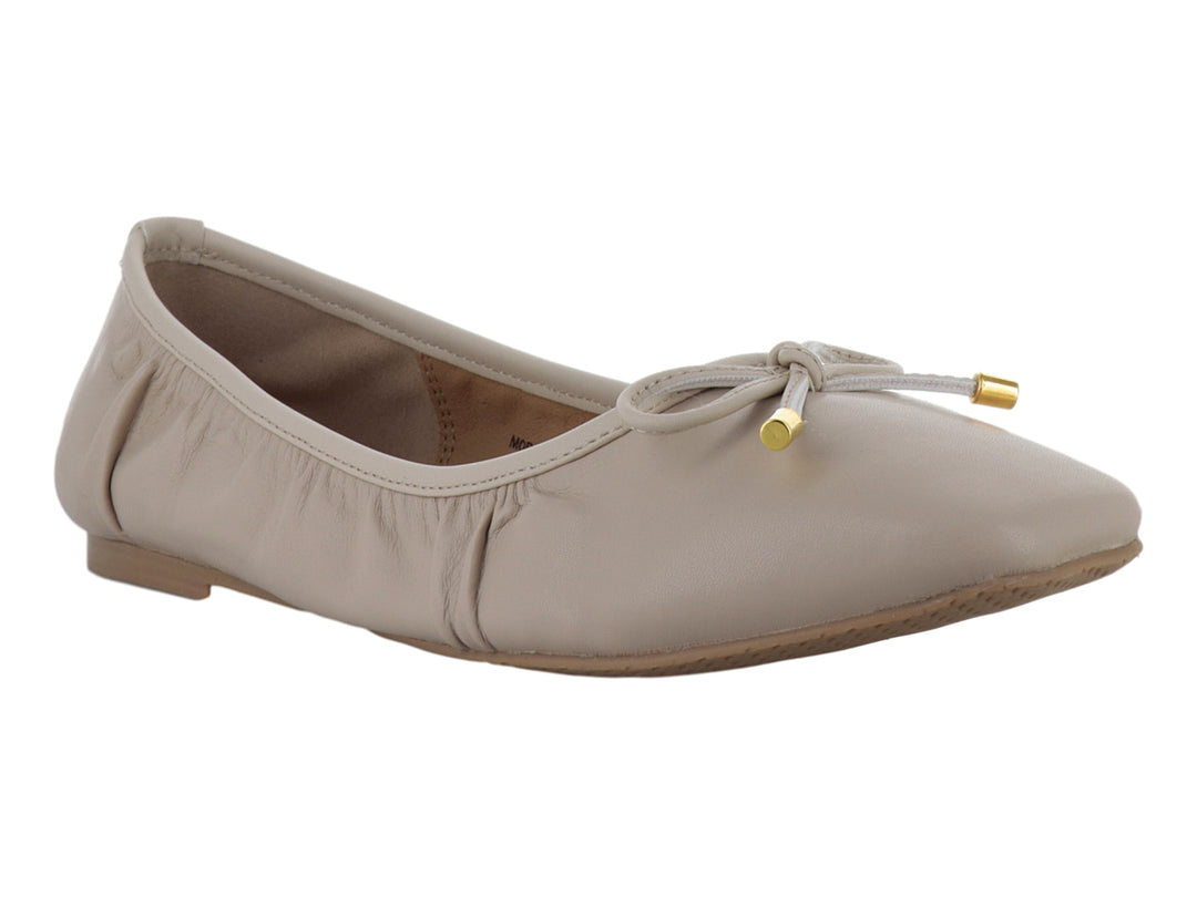 Zapatos planos color beige con moño decorativo y detalles dorados en las puntas.