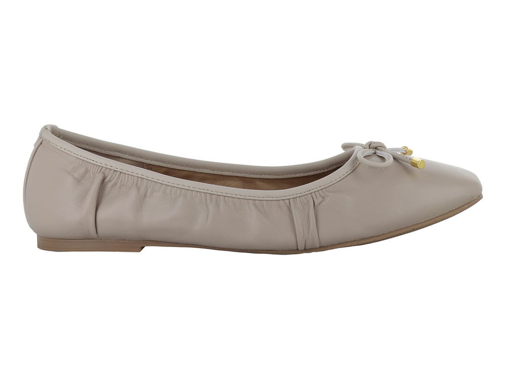 Zapatos planos color beige con moño decorativo y detalles dorados en las puntas.