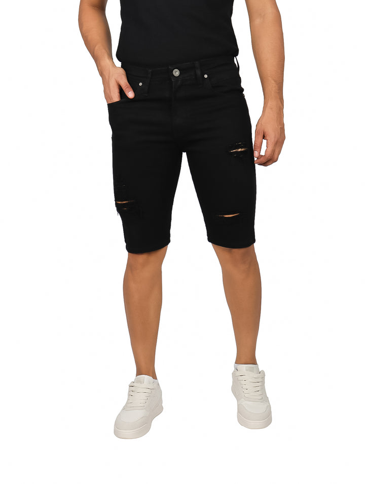 Hombre vistiendo bermuda de mezclilla color negro con detalles rotos en las piernas.