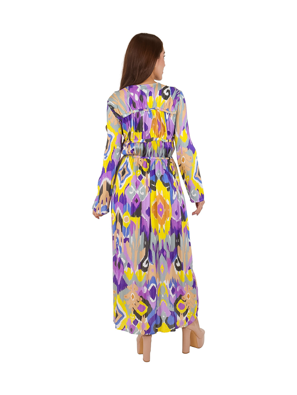 Mujer vistiendo un vestido largo multicolor con patrones geométricos en tonos morado y amarillo.