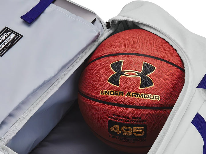 Maleta deportiva Under Armour color gris con detalles en azul, incluye asas y correa para el hombro.