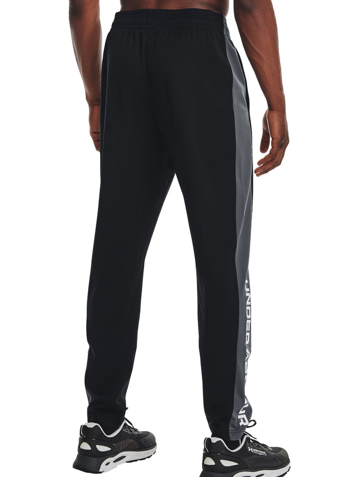 Pantalones deportivos negros Under Armour para entrenamiento con texto blanco en la pierna.